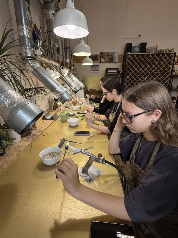Четыре участницы работают за длинным столом с горелками